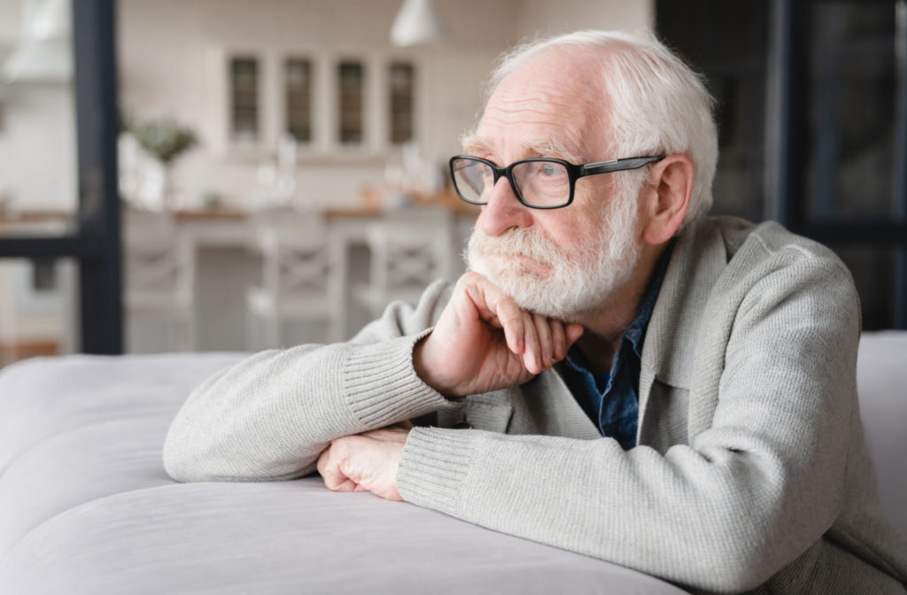 A senior man resting on a pillow gazing outwards.