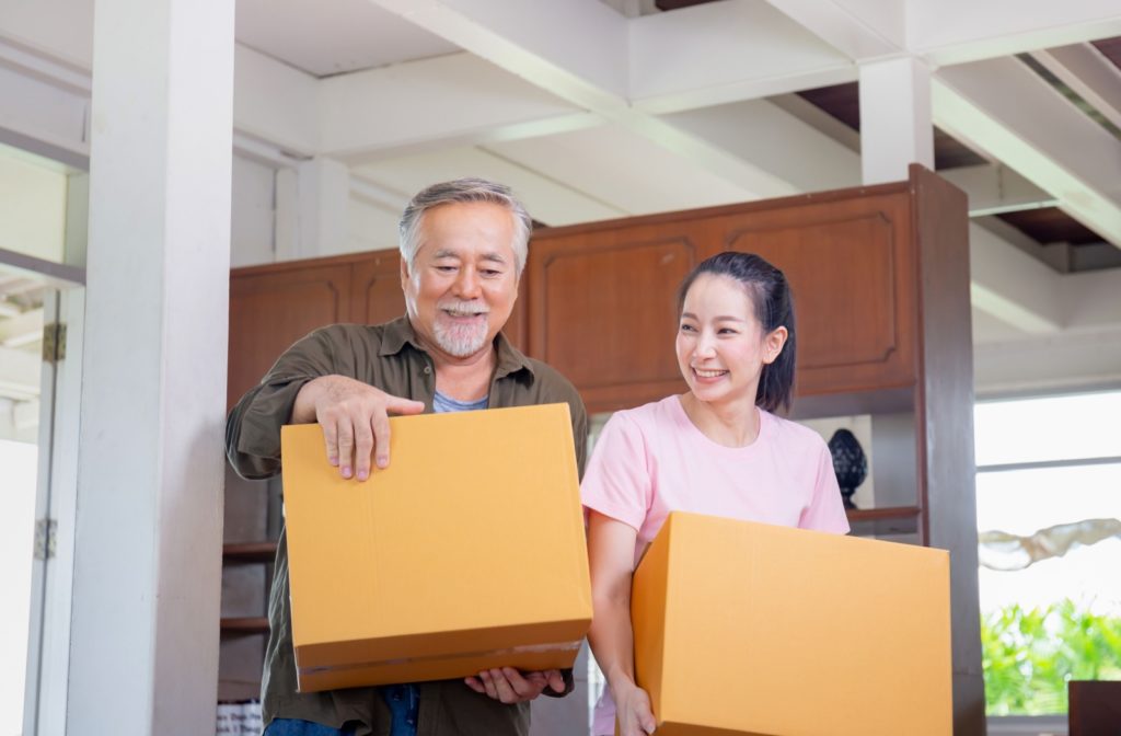 A young woman helping her older adult dad move into assisted living.