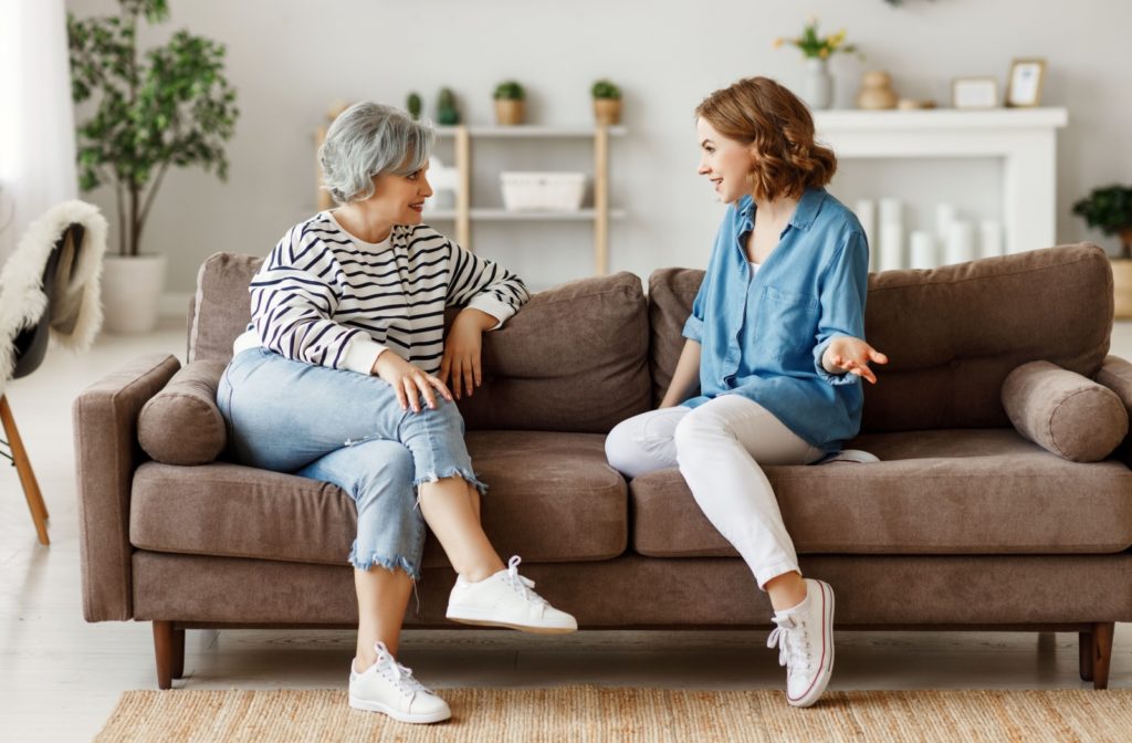 An adult uses enthusiastic body language to communicate interest in conversation while talking to their senior parent.