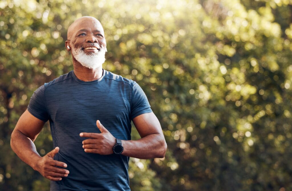 A senior man jogging outdoors, smiling and enjoying a cardio workout.