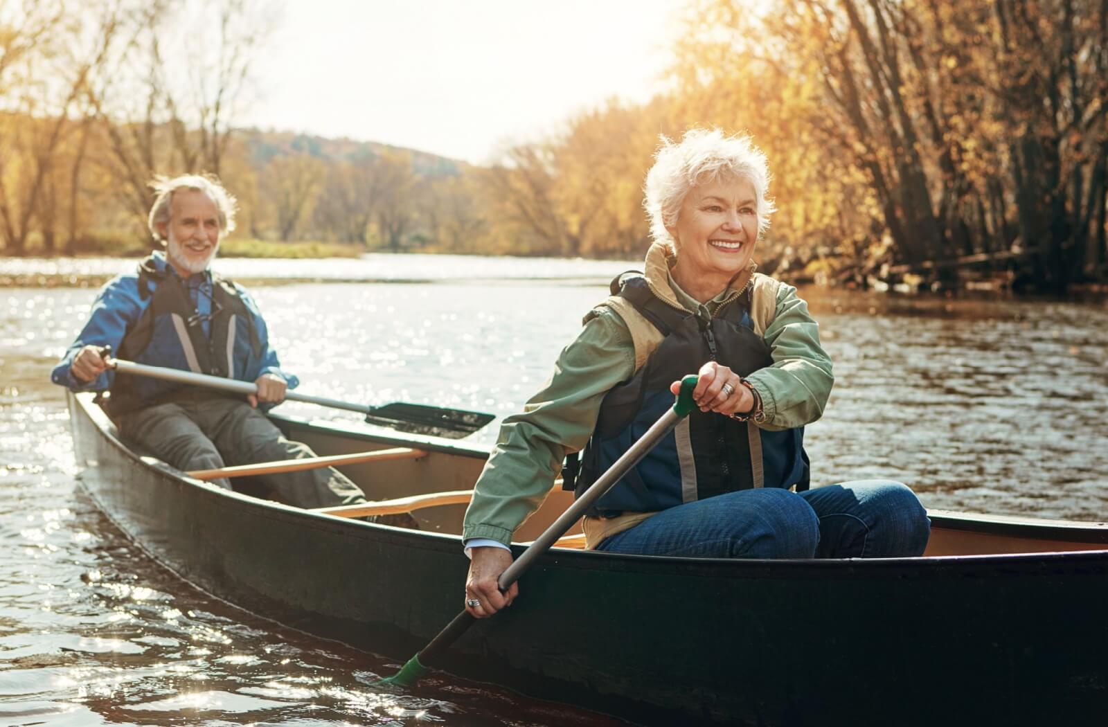 An older couple enjoys paddling down a river as equal parts physical exercise and hobby